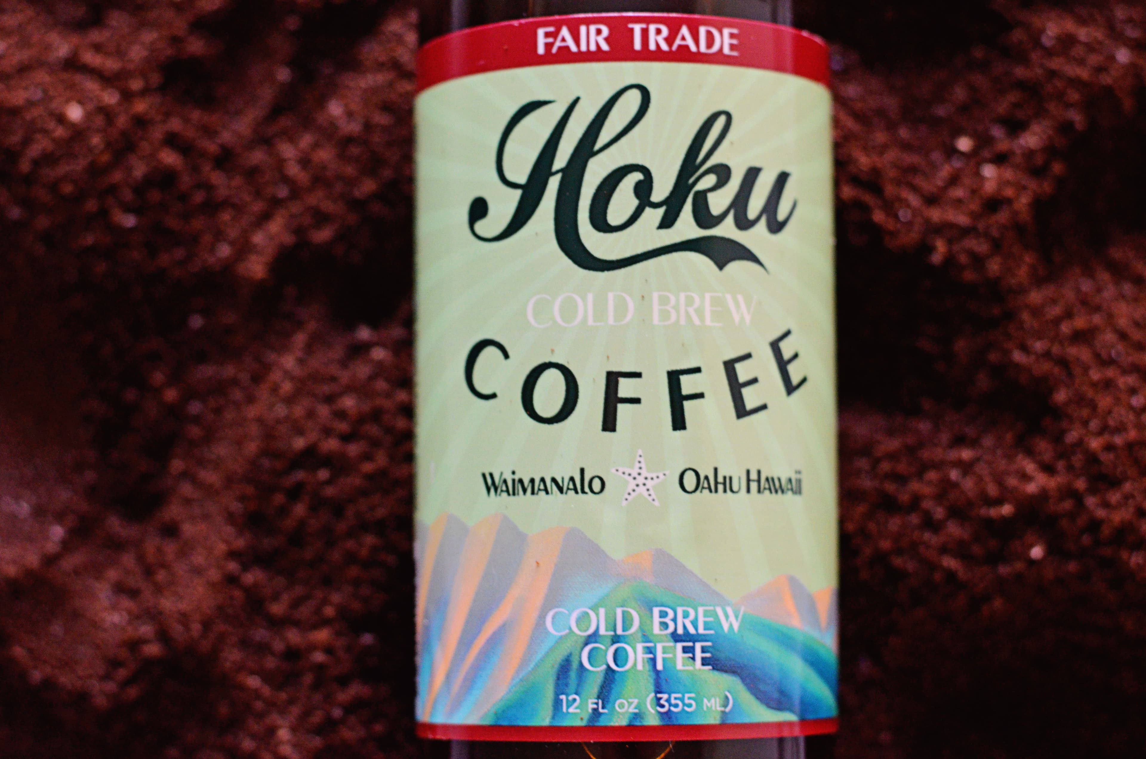 Close-up of a Hoku Fair Trade cold brew label on coffee grounds
